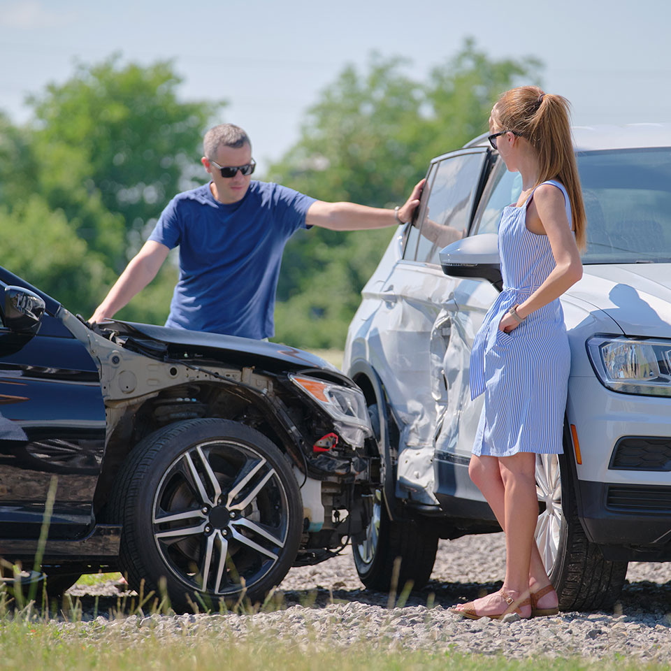 Angry woman and man drivers of heavily damaged vehicles arguing who is guilty in car crash accident on street side. Road safety and insurance concept